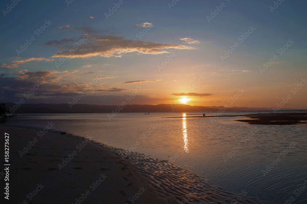 Orange sunset on the beach. Sun reflection on the sea
