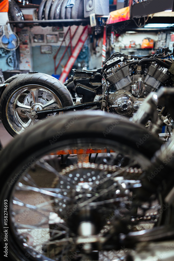 Fototapeta premium Row of disassembled motorcycles set for tuning up and customizing in mechanics workshop