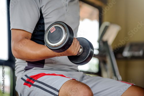 Muscular Young Man Doing Heavy Weight Exercise For Biceps With Dumbbells © toktak_kondesign