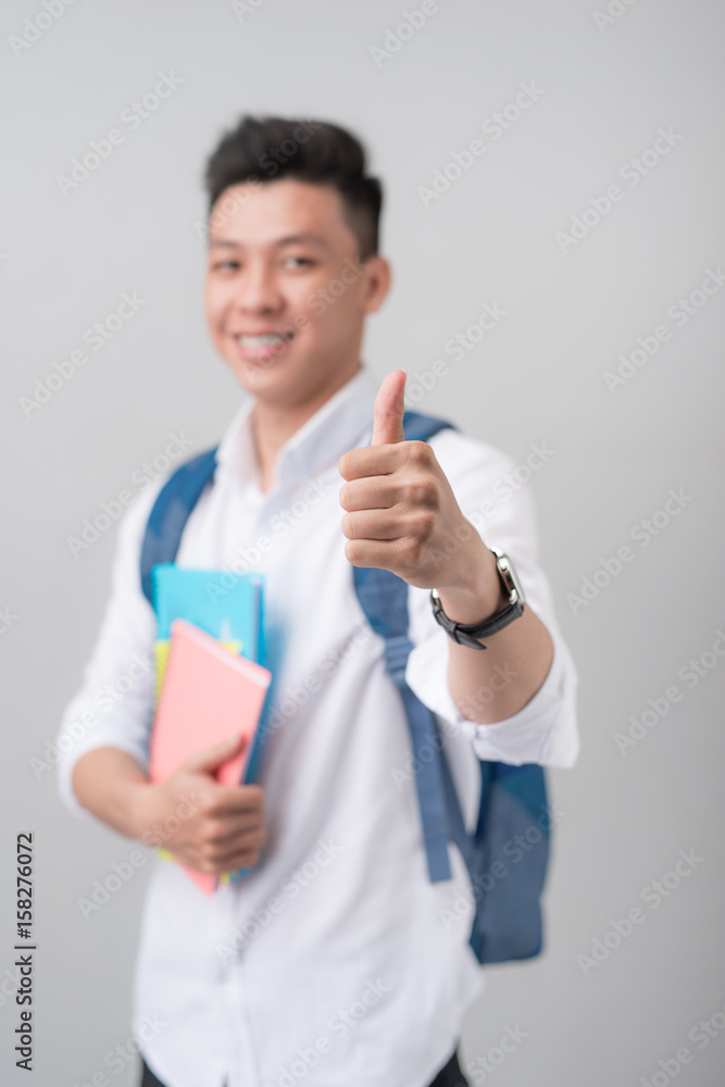 Asian male student making a thumb up sign isolated on white background Asian male student making a thumb up sign isolated on white background