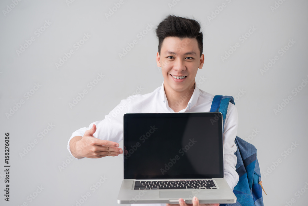 Young asian man in casual clothes holding and showing screen of laptop