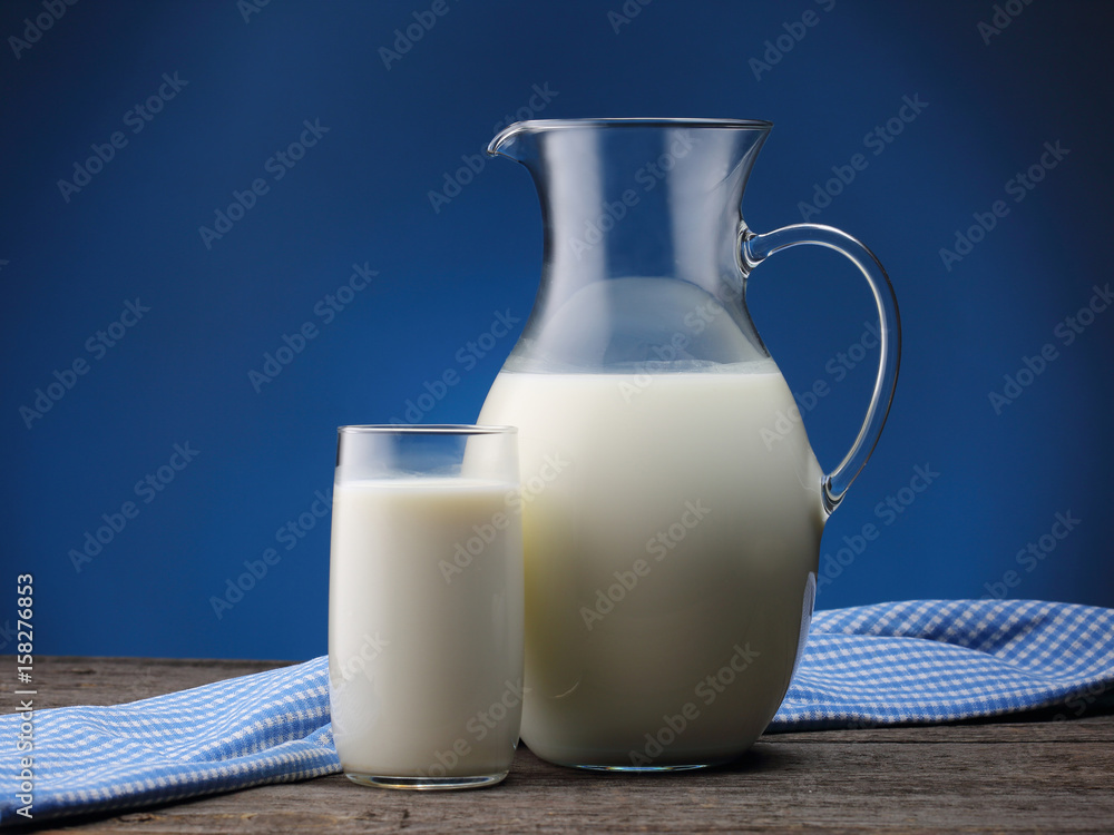 Pitcher and glass with some milk on blue Pitcher and glass with some milk on blue