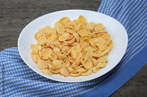 Cornflakes in plate with napkin on wood