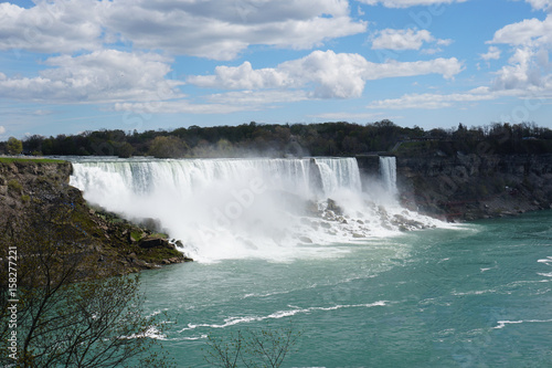 Niagara Falls waterfall on bright spring day with clouds and blue sky as seen from Ontario  Canada