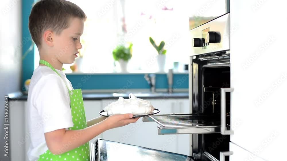Child puts the cake to the oven. Boy prepares a delicious dessert - meringue Child puts the cake to the oven. Boy prepares a delicious dessert - meringue