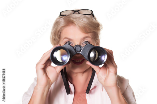 Beautiful elderly woman looking through binoculars over a white background