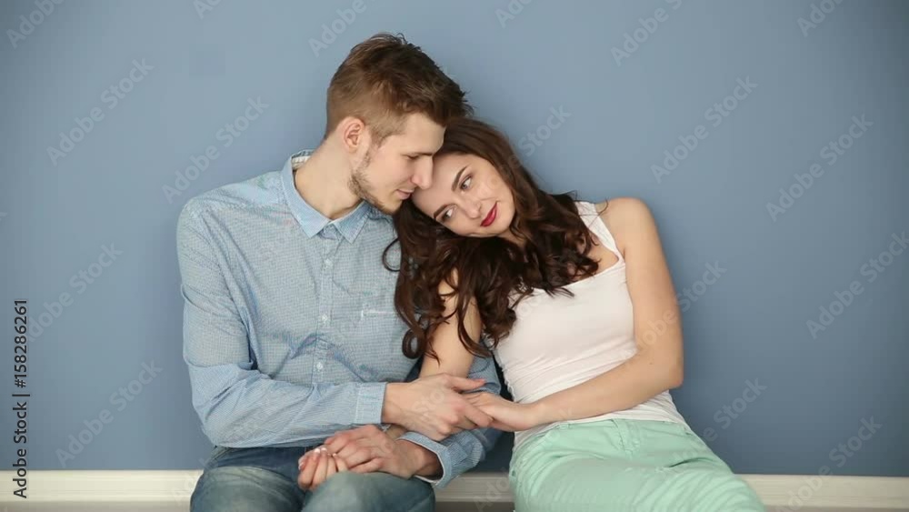 Young couple in love sitting at home by the blue wall Young couple in love sitting at home by the blue wall