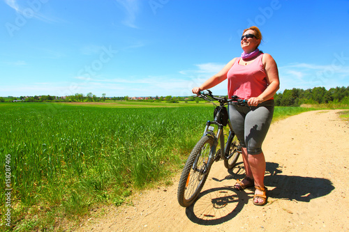 Overweight woman and bicycle. Active people enjoying summer holidays on countryside. 