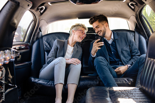 Business woman and business man having laugh in limo