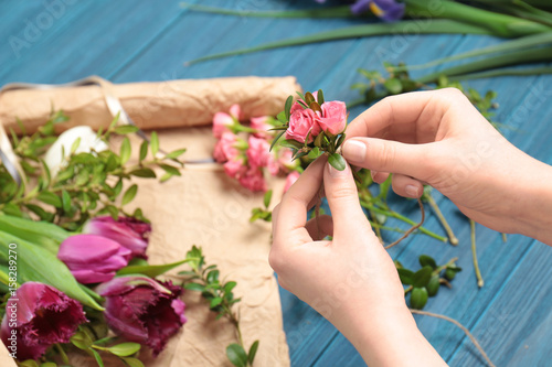 Female florist making floral composition on wooden table
