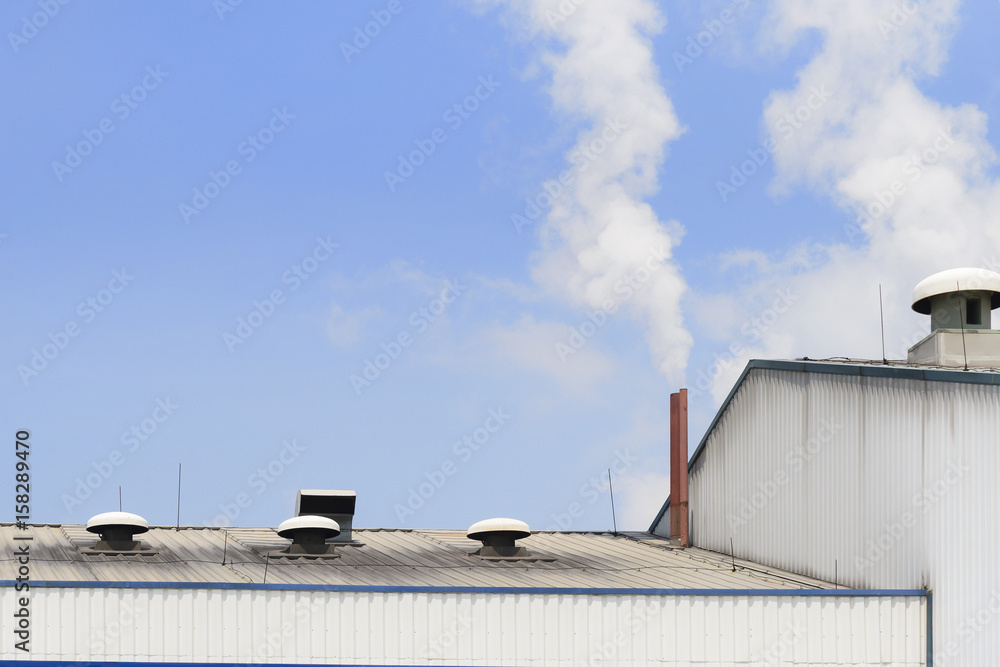 The smokestack of factory building with the smoke and blue sky. Pollution from industrial concept. The smokestack of factory building with the smoke and blue sky. Pollution from industrial concept.