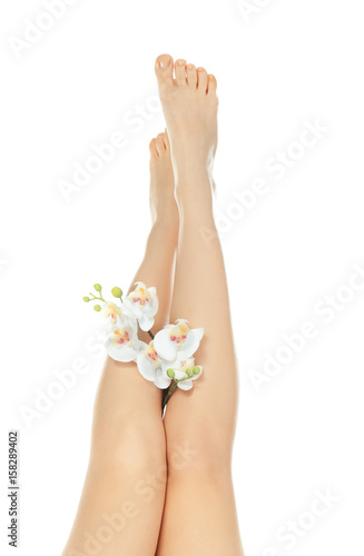 Epilation concept. Legs of beautiful young woman and orchid flowers on white background
