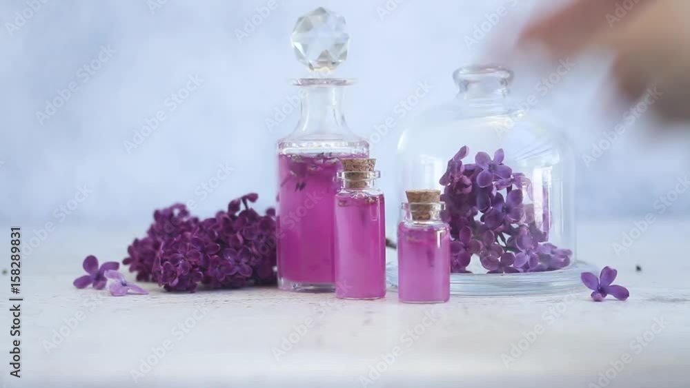 Someone hand placing lilac essence in glass vial, with fresh lilac flowers Someone hand placing lilac essence in glass vial, with fresh lilac flowers