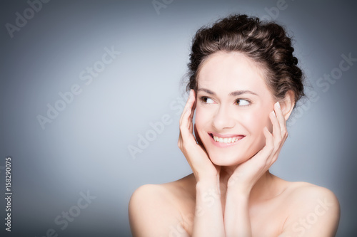 Young smiling woman touching her healthy, fresh face.
