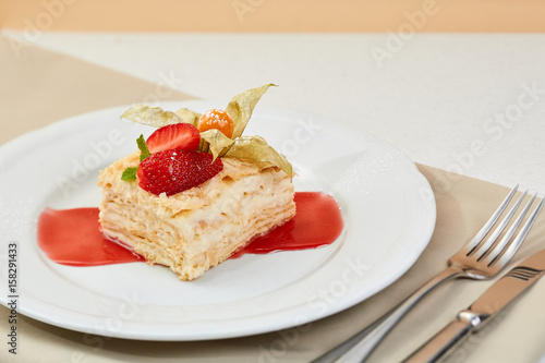 napoleon cake with strawberry, Physalis and jam on white plate. mille-feuille dessert with fresh berries and cutlery. photo