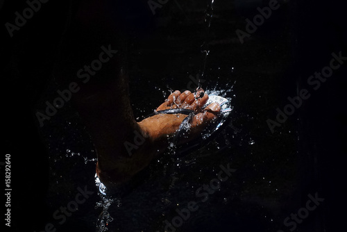 Wash The Feet With Flowing Clear Water In Dramatic Light Over Black Background