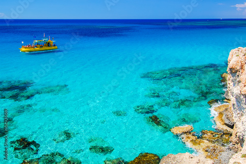 Tourist boat on azure sea water near Cavo Greko peninsula, Cyprus island