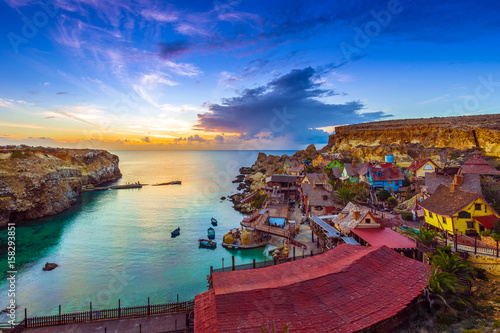 Mellieha, Malta - Skyline view of the beautiful Popeye Village at Anchor Bay at sunset with amazing colorful clouds and sky photo
