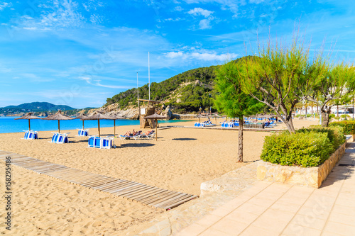 Sandy beach with umbrellas and sunbeds in Cala San Vicente bay on sunny summer day, Ibiza island, Spain © pkazmierczak