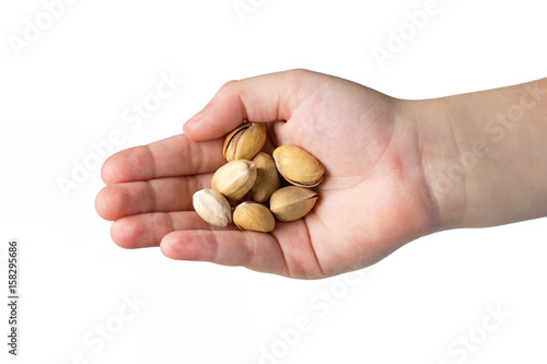 Roasted pistachios in the hands of the child isolated on white background.