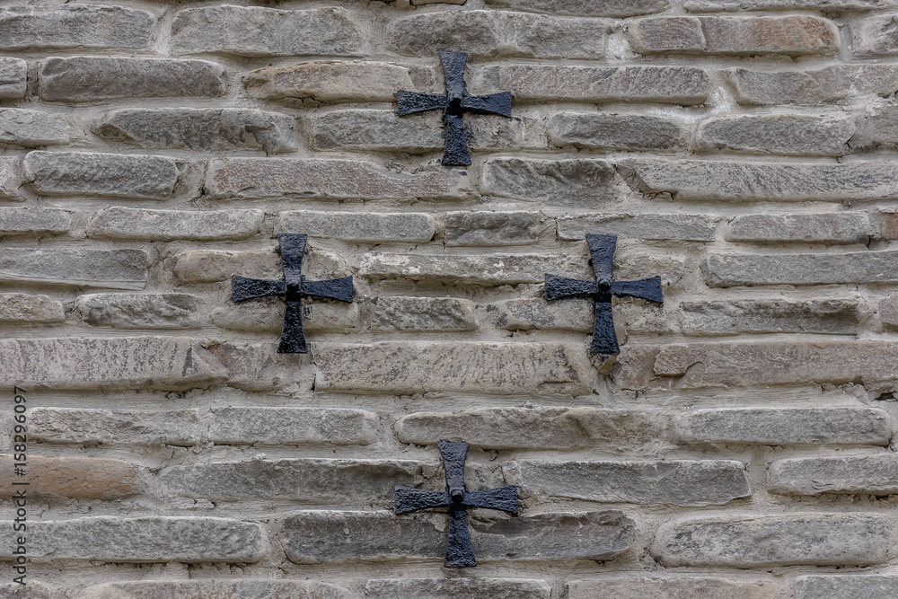 Iron cross hanging on a stone wall, background