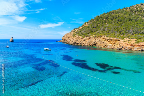 View of Cala Benirras bay with fishing boat on azure blue sea water, Ibiza island, Spain