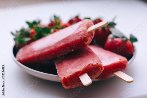 Delicious ice cream sticks with strawberries on a white background 