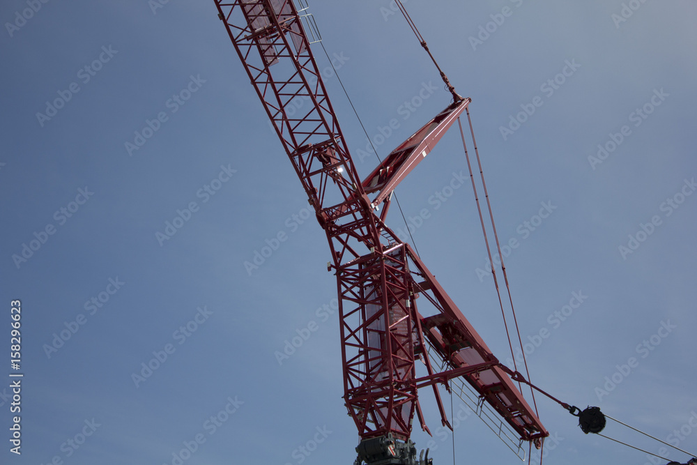 Red industrial construction crane against blue sky with copy space Red industrial construction crane against blue sky with copy space