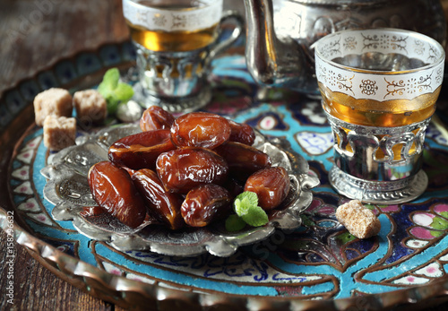 Фотография Ripe dates and sweet green tea. Toned image