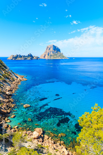 View of Cala d'Hort bay with beautiful azure blue sea water and Es Vedra island in distance, Ibiza island, Spain photo