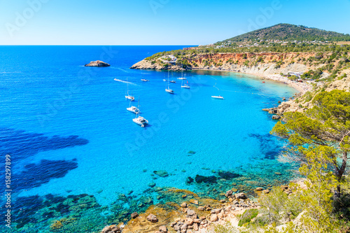 Fototapeta Naklejka Na Ścianę i Meble -  Sailing boats on Cala d'Hort bay with beautiful azure blue sea water, Ibiza island, Spain