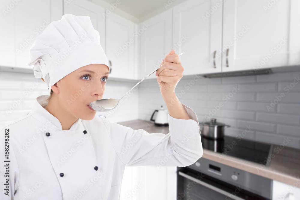young woman in chef uniform tasting something in kitchen young woman in chef uniform tasting something in kitchen