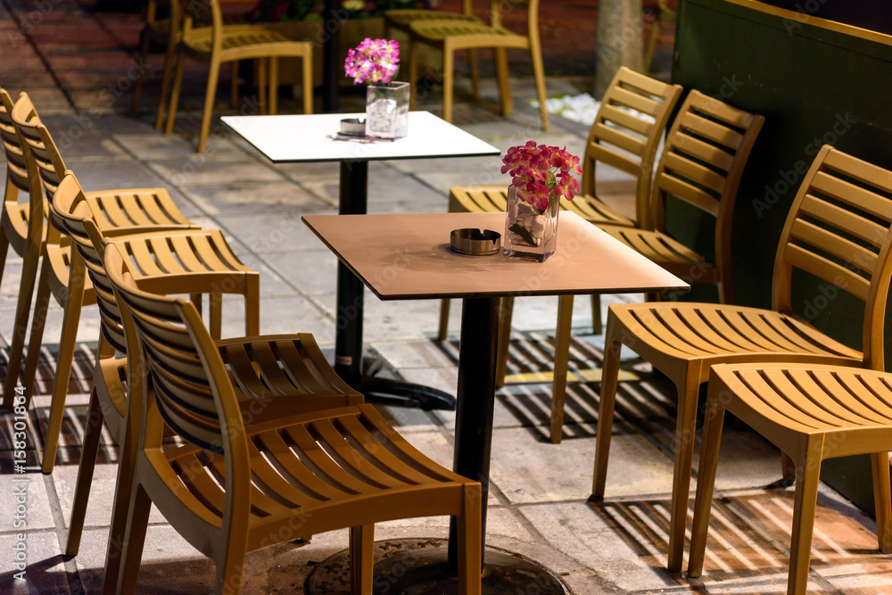 Wooden chairs and tables with flowers at night