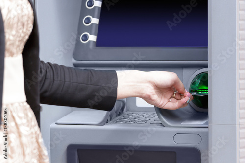 Close up hand inserting card into ATM
