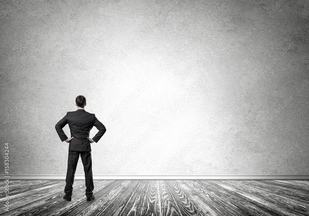 Obraz premium Businessman with hands on waist standing with back and looking a