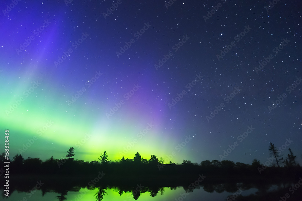 Northern lights vibrant in night sky full of stars and faint milky way ...