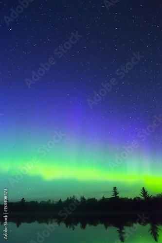Vertical composition of northern lights and deep blue starry night sky