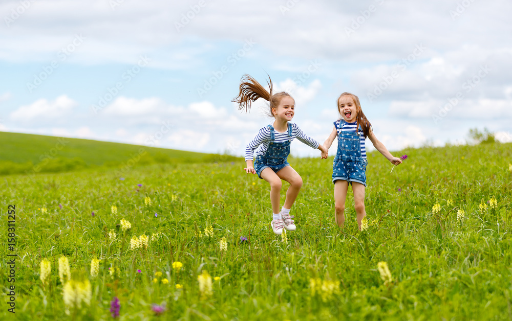 happy children twins sisters jumping and laughing in summer happy children twins sisters jumping and laughing in summer