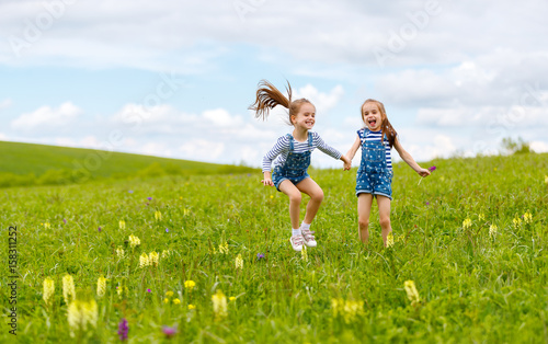 happy children twins sisters jumping and laughing in summer