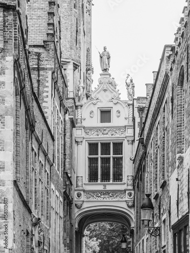 Bridge crossing between buildings over narrow Blinde-Ezelstraat  aka Blind donkey street  near Burg square  Bruges  Belgium. Black and white image.