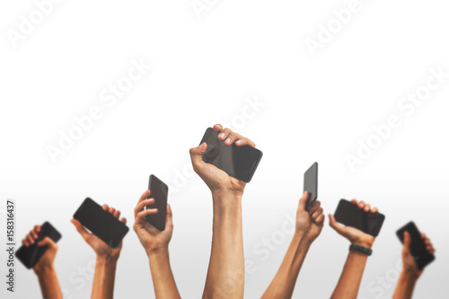 group of people's hands holding phones and rising them up against a white backgroud