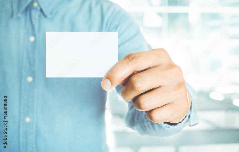 Young business man holding white business card on modern office blur background. Young business man holding white business card on modern office blur background.