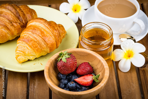 Cup of coffee and croissants on wooden background.