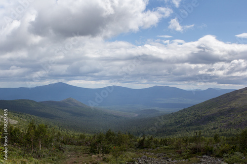 Summer in the mountains. Mountain ranges over the forest. Panoramic view of the mountains.