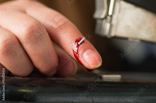 Close up of a youn woman injured her finger using a stapler, bleeding