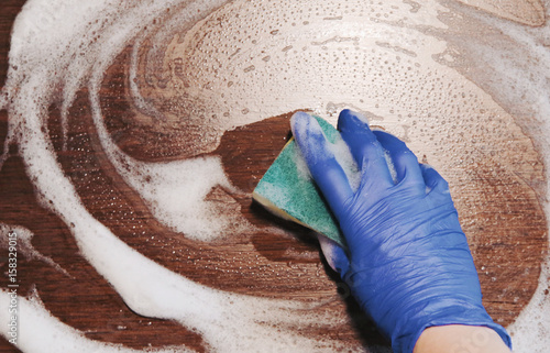 Closeup on woman's hands in blue protective rubber gloves cleaning kitchen and tiles. Instagram