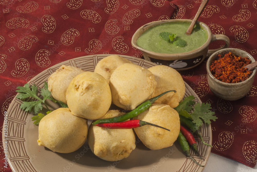 Batata Vada with garlic and mint chutney and chilli on white plate Batata Vada with garlic and mint chutney and chilli on white plate