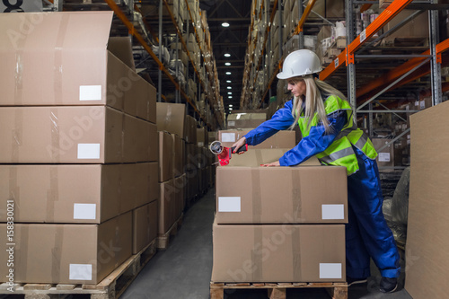 Female warehouse worker packing boxes in storehouse