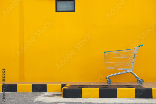 Empty shopping cart parking on yellow background with copyspace. retail store.