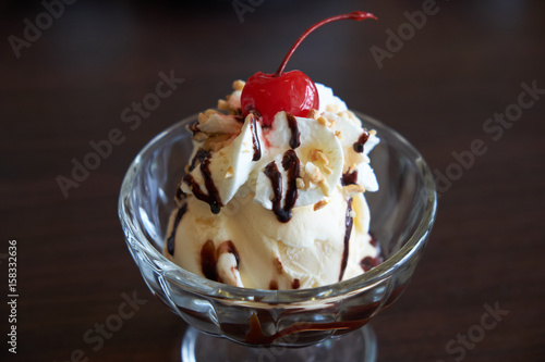 Ice cream chocolate and vanilla sundae topping with red cherry.